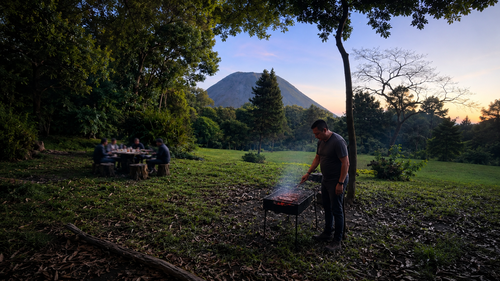 An outdoor barbecue and shared table in the forest with a volcano rising in the distance at golden hour in El Salvador