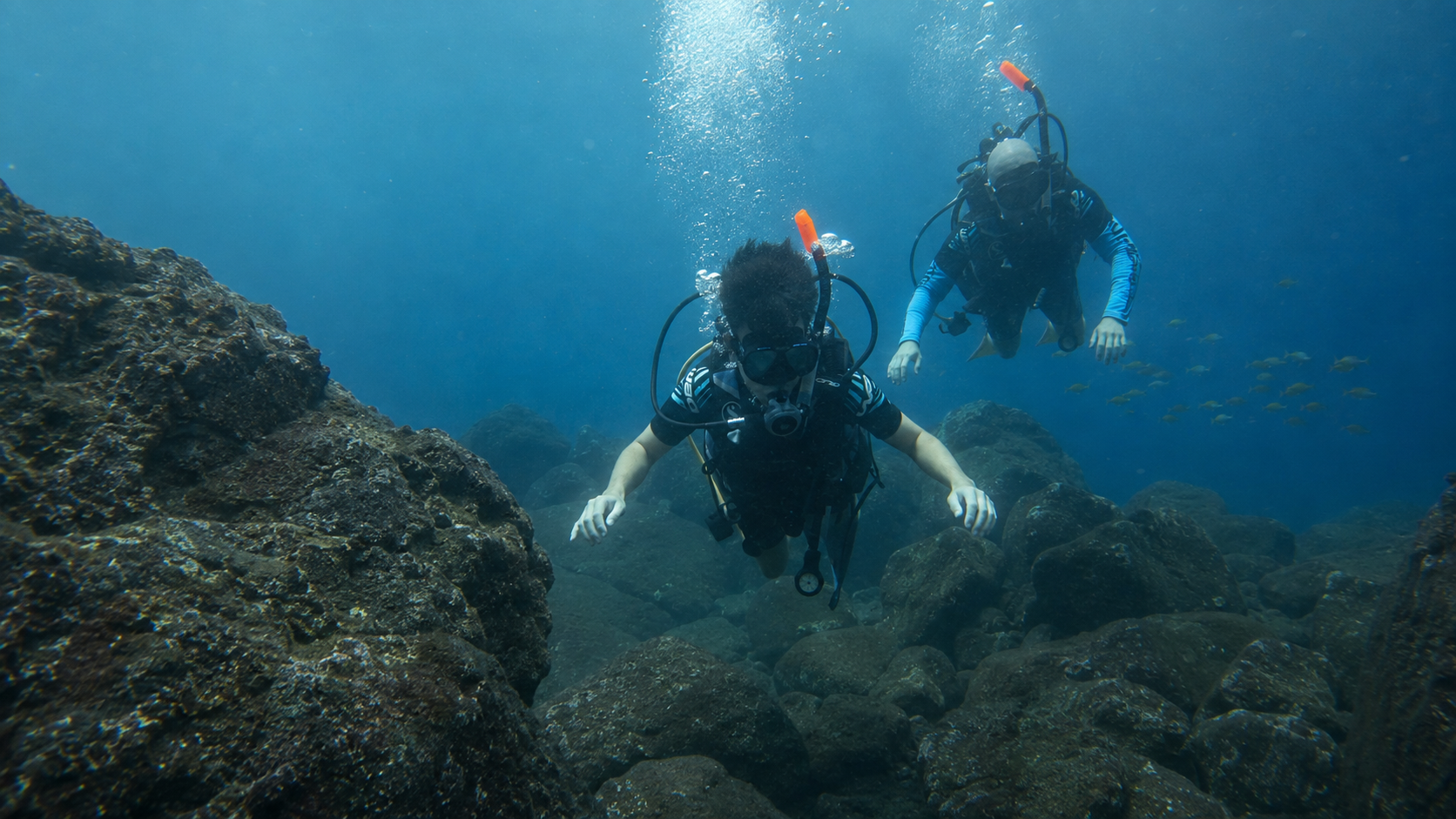 Two scuba divers exploring underwater volcanic rock formations in El Salvador.