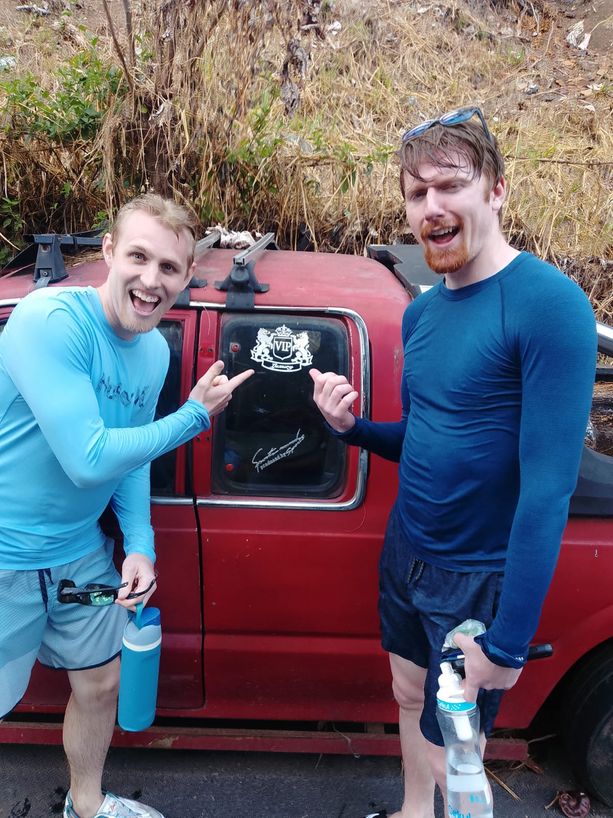 Two friends laughing next to the VIP Tours vehicle after a hike