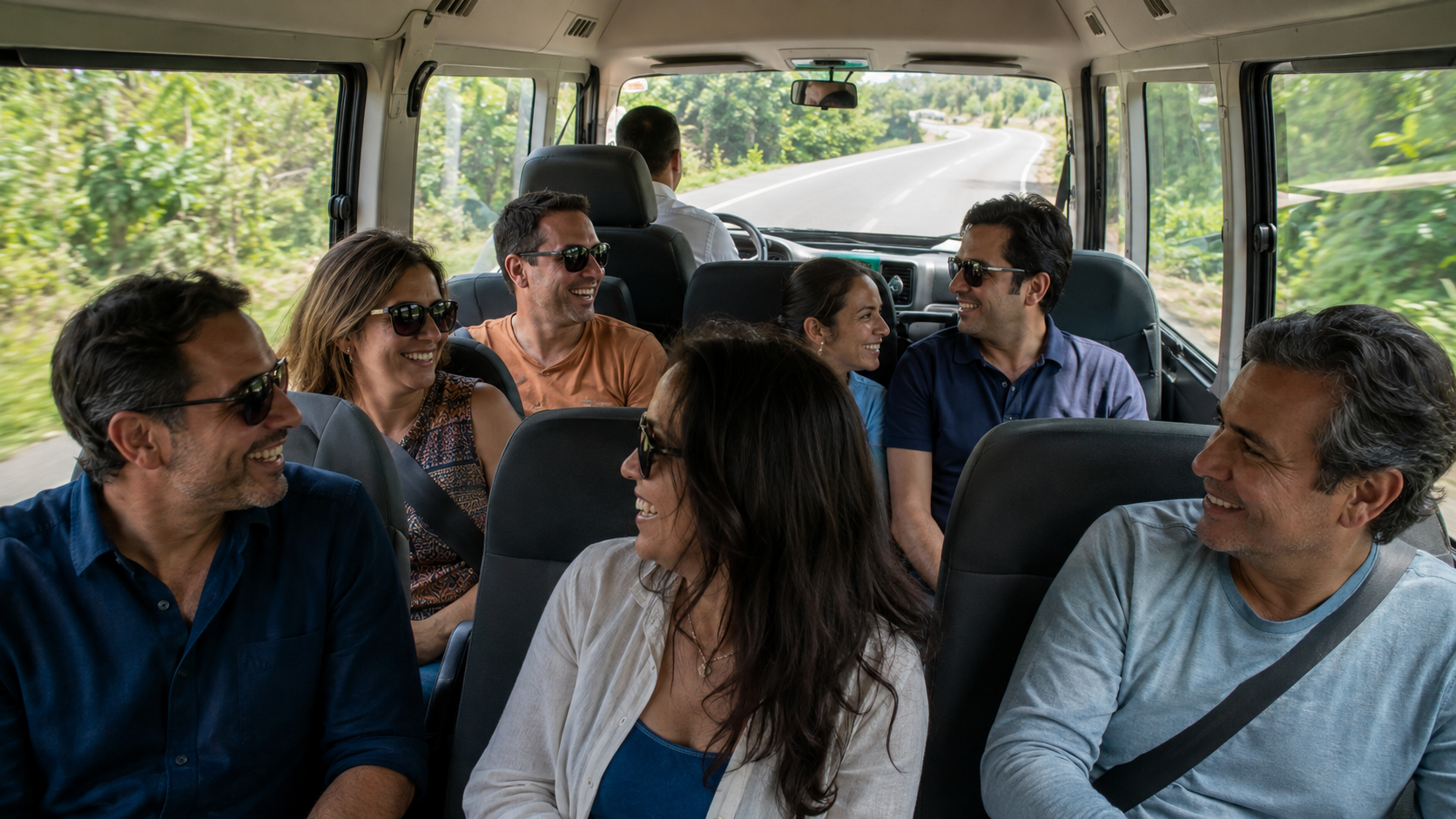 A group of friends and family traveling together inside a private vehicle in El Salvador, talking and laughing while a professional driver drives along a green mountain road